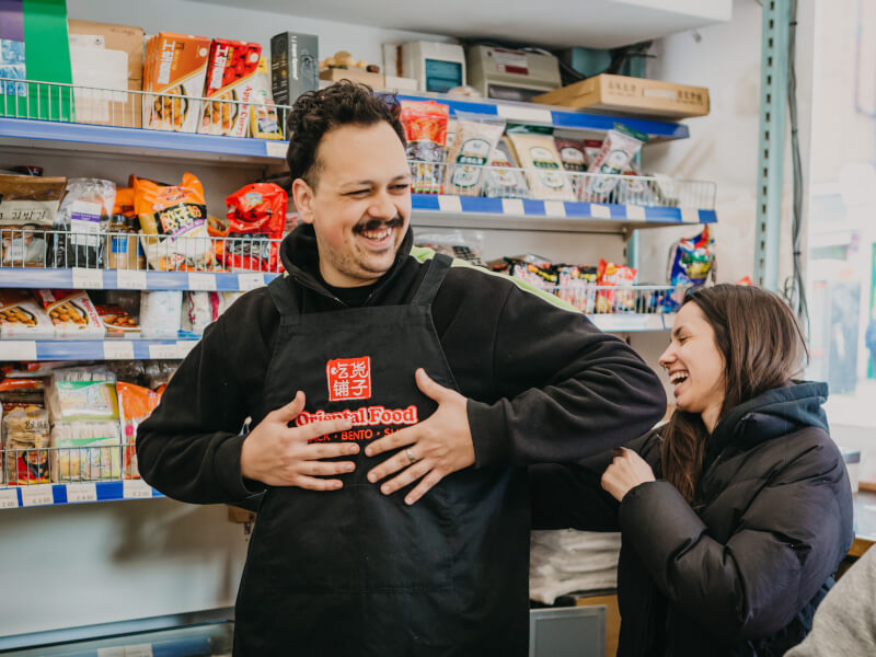 A woman tying a mans apron at a cooking class. 
